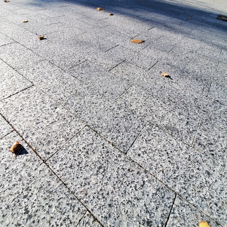 Application image for Granite - White House - Pavers. The image shows this product being used in a driveway pavers application. The surface finish shown is flamed. Dominant colors shown are gray and white. The color mix creates a cool feeling.