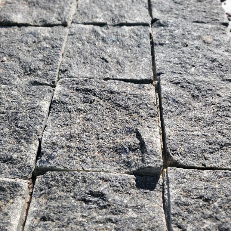 Application image for Gabbro - Dark Magma - Cobblestones. The image shows this product being used in a path pavers application. The dominant color shown is gray. The color mix creates a cool feeling.