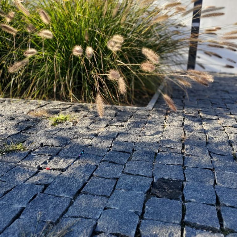 Application image for Gabbro - Dark Magma - Cobblestones. The image shows this product being used in a patio pavers application. The dominant color shown is gray. The color mix creates a warm feeling.