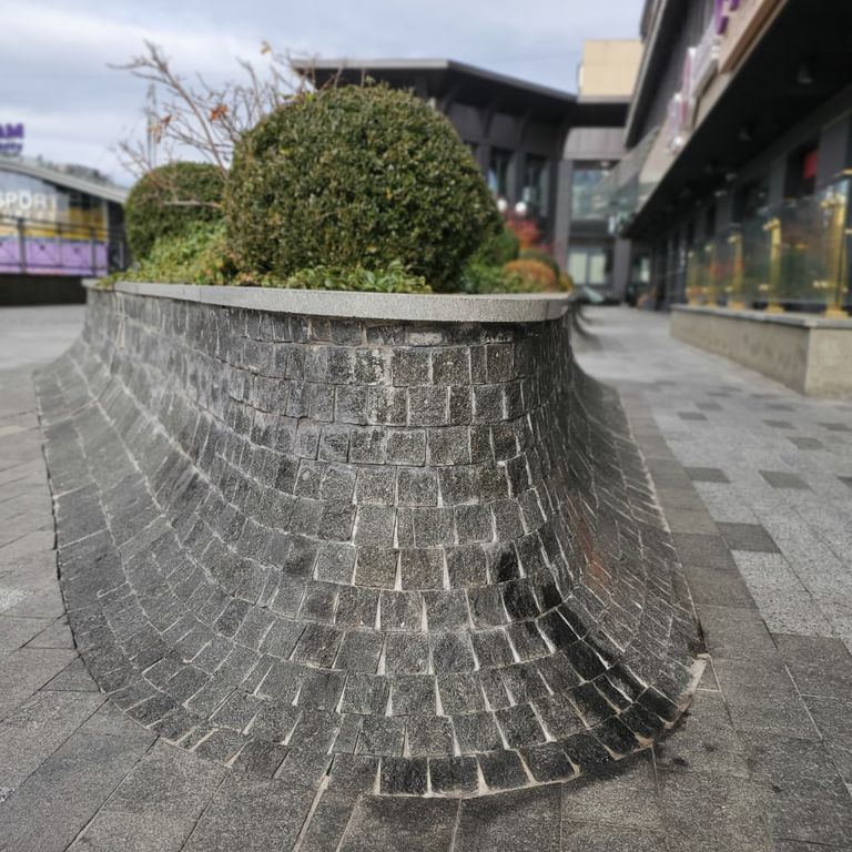 Application image for Granite - Gabbro - Dark Magma - Cobblestones. The image shows this product being used for thin veneer and public area. The dominant color shown is gray. The color mix creates a warm feeling.