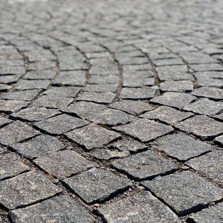 Application image for Gabbro - Dark Magma - Cobblestones. The image shows this product being used in a patio pavers application. The dominant color shown is gray.