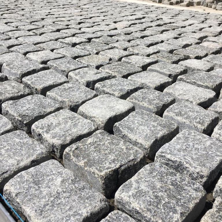 Application image for Gabbro - Dark Magma - Cobblestones. The image shows this product being used in a patio pavers application. The surface finish shown is tumbled. The dominant color shown is gray.