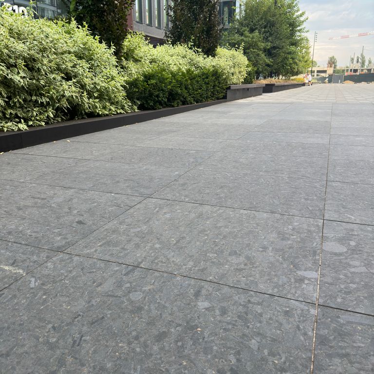 Application image for Granite - Labradorite - Blue Seven Oceans - Pavers. The image shows this product being used for path pavers and public area. The surface finish shown is honed. The dominant color shown is gray. The color mix creates a warm feeling.