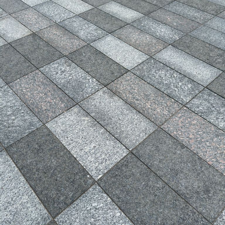 Application image for Granite - Gray Leopard. The image shows this material being used for driveway pavers, path pavers and patio pavers. The dominant color shown is gray. The color mix creates a cool feeling.