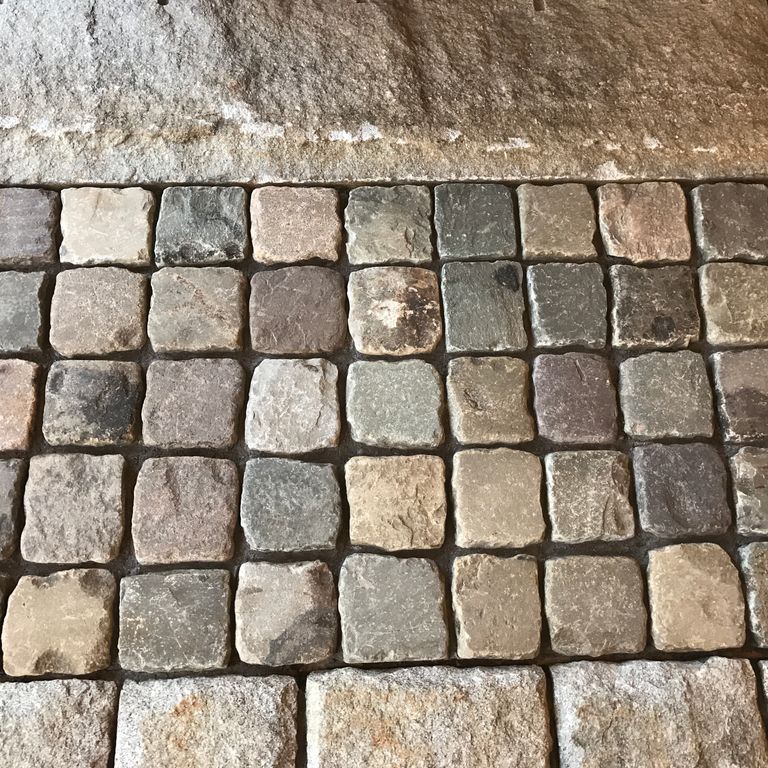 Application image for Reclaimed European Sandstone Cobblestones - Square - Worn Surface. The image shows this product being used in a public area application. The surface finish shown is . Dominant colors shown are brown and gray. The color mix creates a warm feeling.