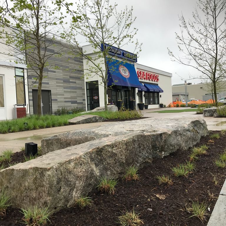 Application image for New England Fieldstone Boulders & Ledgestone - Seating & Benches. The image shows this product being used for seating & benches and landscape boulders & ledge. The surface finish shown is weathered. The dominant color shown is gray. The color mix creates a warm feeling.