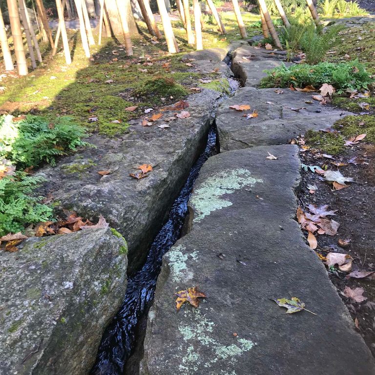 Application image for New England Fieldstone Boulders & Ledgestone - Pool/Pond Coping. The image shows this product being used for water features and landscape boulders & ledge. The surface finish shown is weathered. The dominant color shown is gray. The color mix creates a warm feeling.