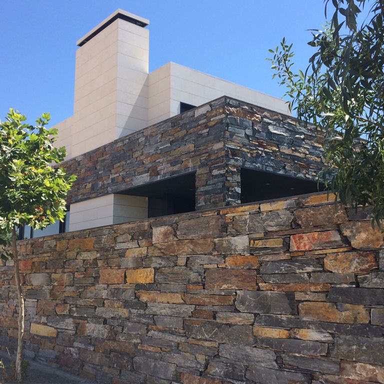Application image for Slate - Iberian Gray - Veneer. The image shows this product being used for full bed veneer and thin veneer. The surface finish shown is split-face. Dominant colors shown are black and brown. The color mix creates a warm feeling.