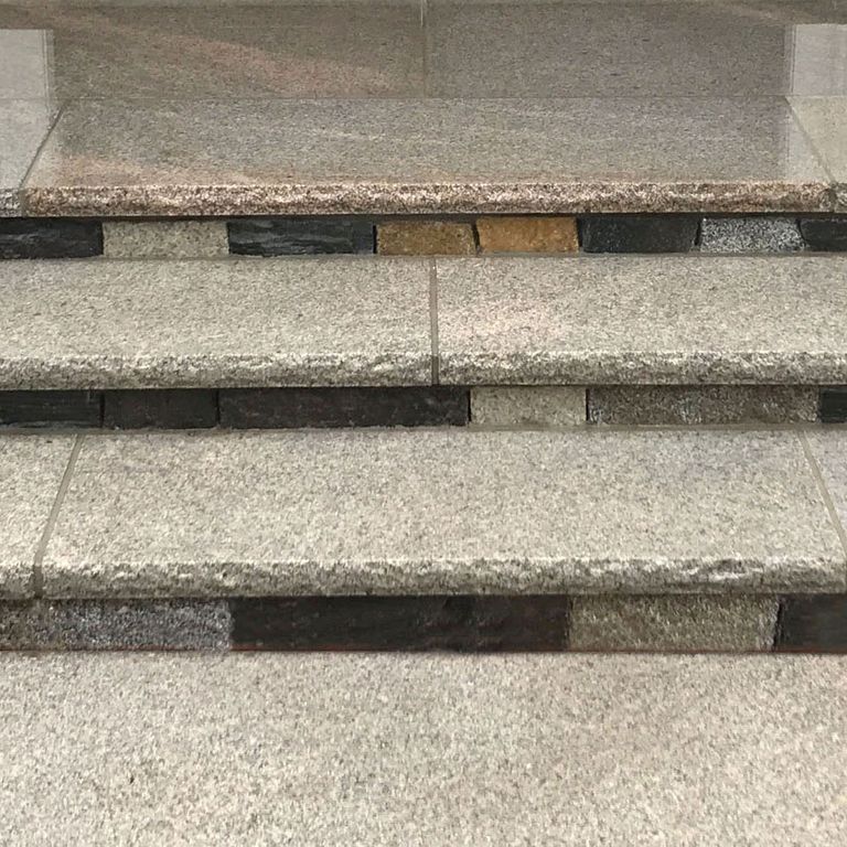 Close-up image for Cape Neddick Granite Clear - Rockfaced Treads. The surface finish shown is flamed. Dominant colors shown are beige, gray and tan; with brown and cream secondaries. The color mix creates a warm feeling. Speckled and fine speckled color patterns.
