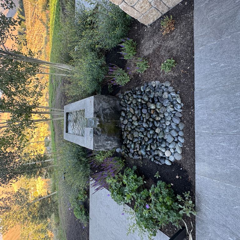 Application image for Granite - Jet Mist - Water Feature. The image shows this product being used for water features, garden accents and sculpture & carvings. The surface finish shown is split-face. The dominant color shown is gray. The color mix creates a warm feeling.