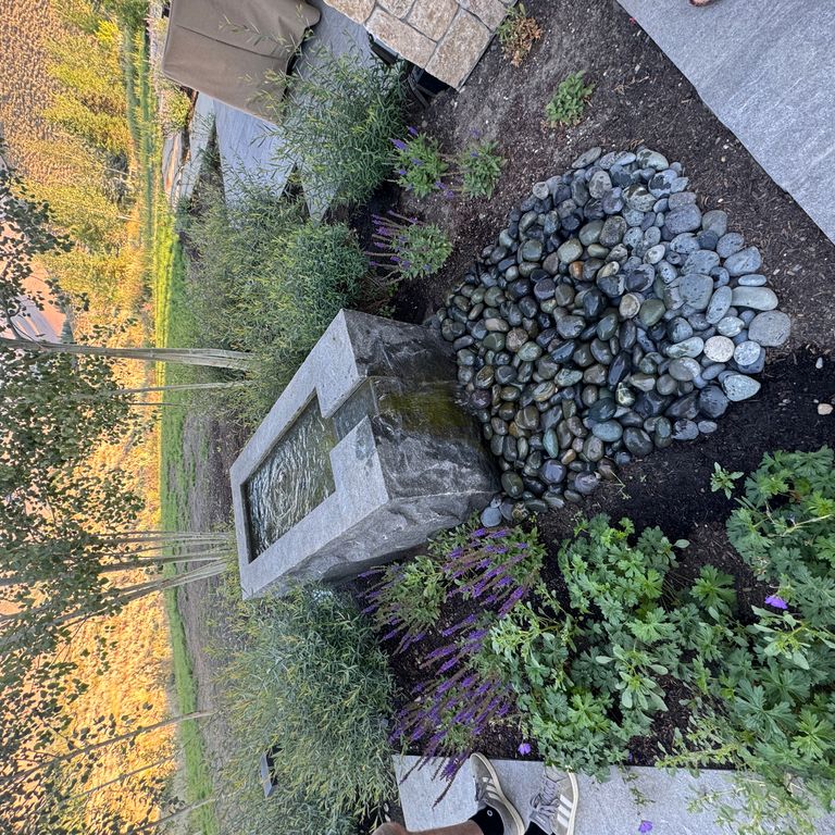 Application image for Granite - Jet Mist - Water Feature. The image shows this product being used for water features, garden accents and sculpture & carvings. The surface finish shown is split-face. The dominant color shown is gray. The color mix creates a warm feeling.
