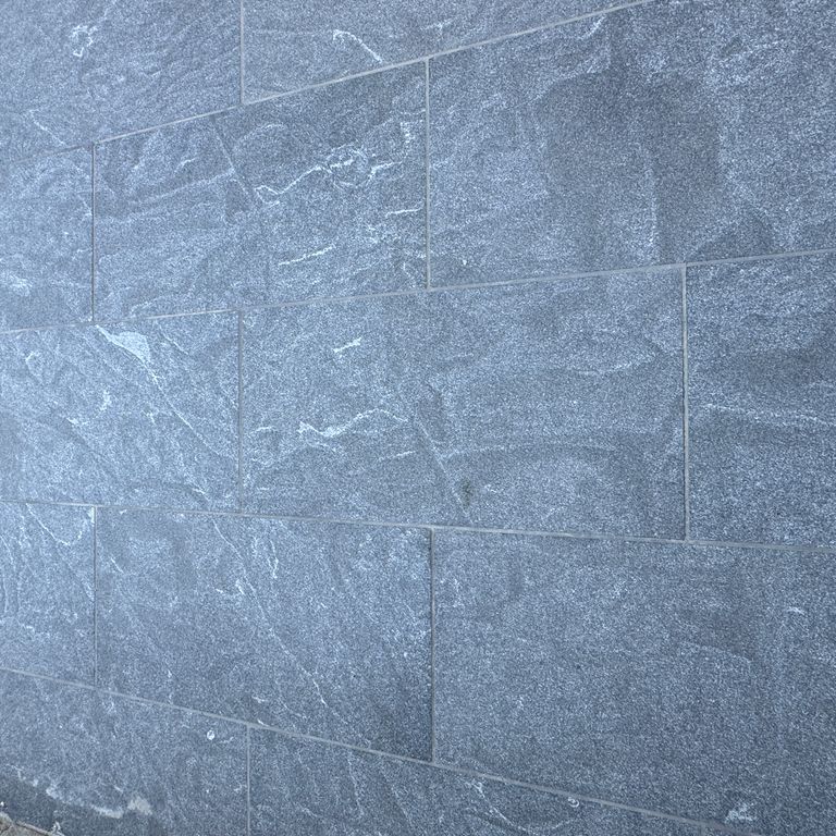 Best close-up image for Granite - Jet Mist - Pavers. The image shows this product being used in a patio pavers application. The surface finish shown is flamed. The dominant color shown is gray.