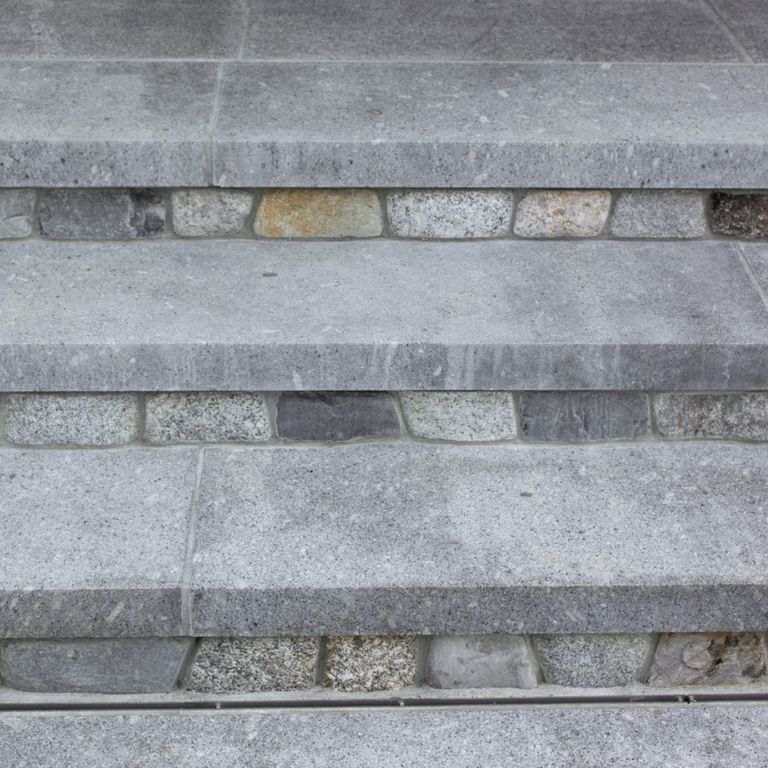 Close-up image for Oak Mountain Granite Treads. The surface finish shown is flamed. Dominant colors shown are blue and gray; with a white secondary. The color mix creates a cool feeling. Regular, speckled and fine speckled color patterns. Contains mineral inclusions.