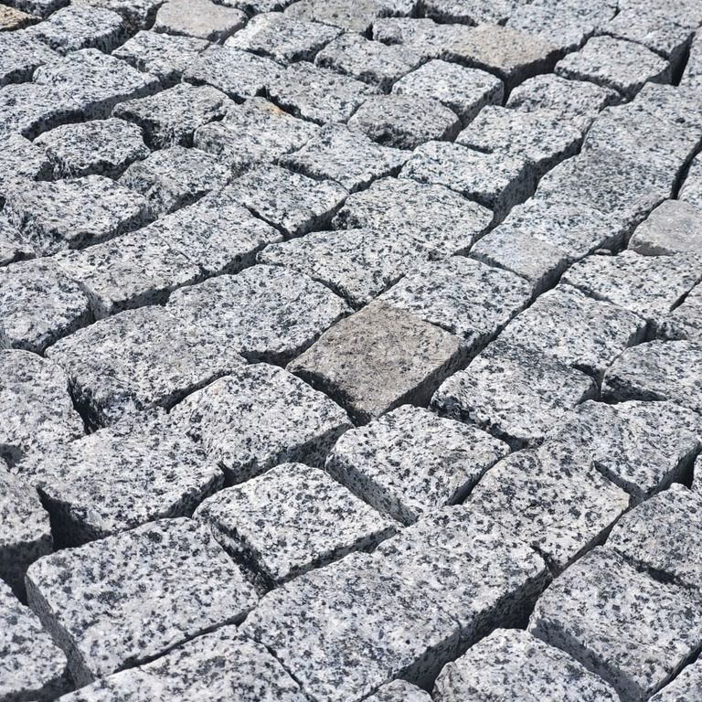 Application image for White House Granite - Tumbled Cobblestones. The image shows this product being used in a patio pavers application. The dominant color shown is white. The color mix creates a cool feeling.