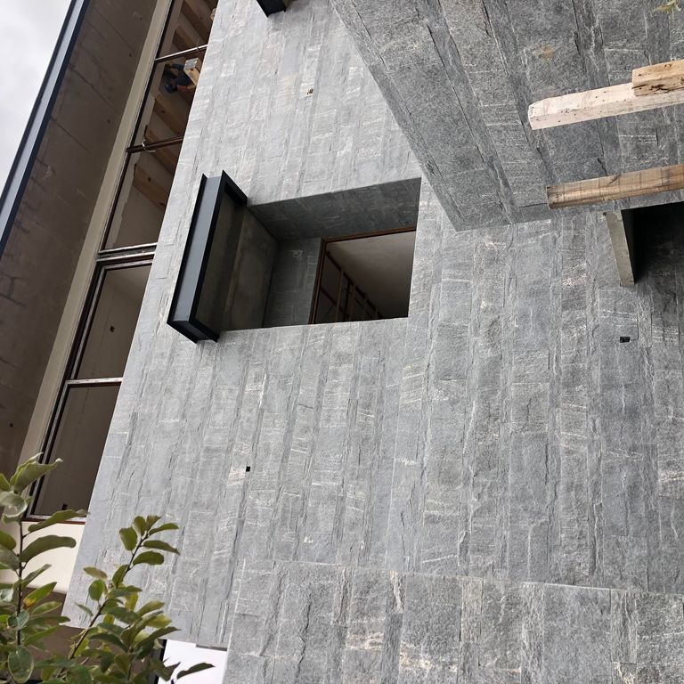 Application image for Brazilian Lucerna Gneiss - Veneer. The image shows this product being used in a full bed veneer application. The surface finish shown is split-face. The dominant color shown is gray. The color mix creates a cool feeling.