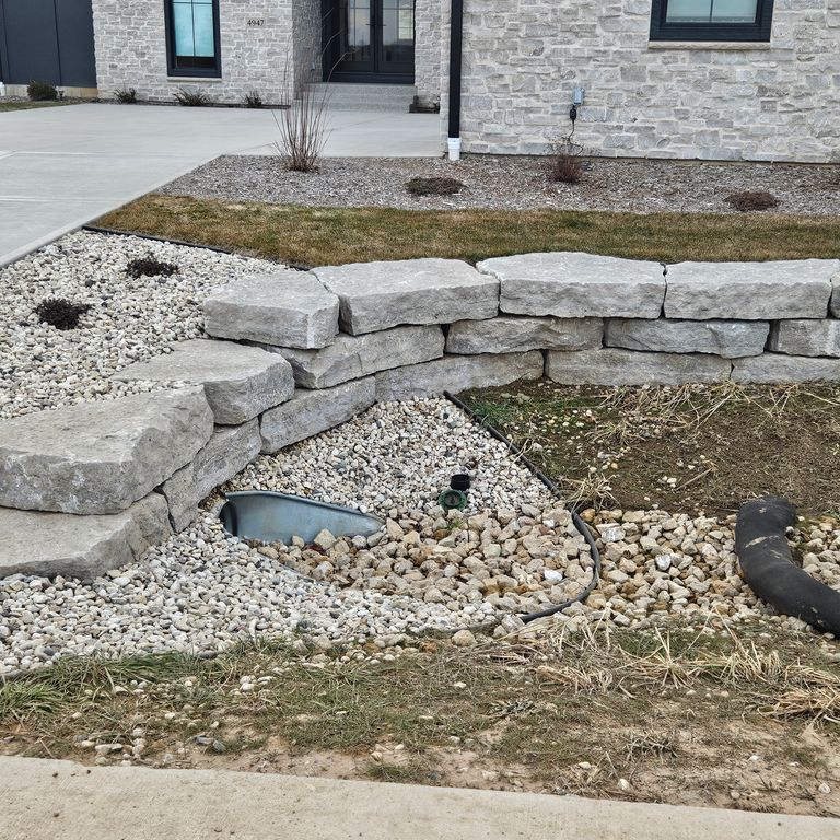 Feature image for Rustic Gray Limestone - Wallstone. The image shows this product being used in a landscape wallstone application. The surface finish shown is natural cleft. The dominant color shown is gray. The color mix creates a warm feeling.