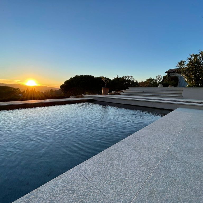 Application image for Veneto Olivo Limestone - Pool Coping. The image shows this product being used for pool coping and pool deck pavers. The surface finish shown is flamed. The dominant color shown is gray. The color mix creates a warm feeling.